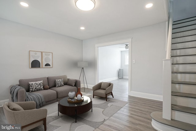 living area featuring recessed lighting, baseboards, radiator heating unit, and wood finished floors