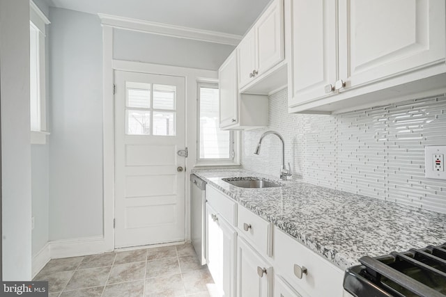 kitchen featuring light stone counters, a sink, white cabinetry, stainless steel dishwasher, and decorative backsplash