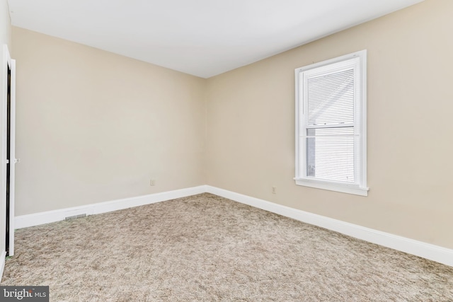 carpeted spare room with visible vents and baseboards