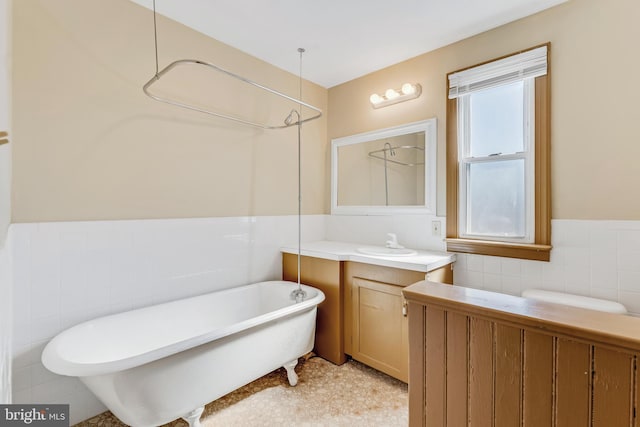 full bath with tile walls, a freestanding bath, wainscoting, vanity, and walk in shower