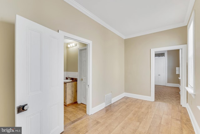 unfurnished room with ornamental molding, visible vents, light wood-style flooring, and baseboards