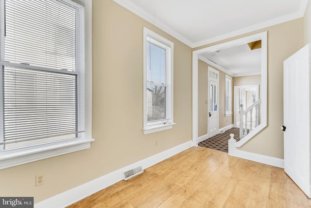 entrance foyer featuring light wood-style flooring, visible vents, baseboards, and ornamental molding