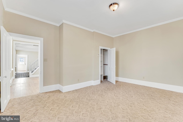 carpeted empty room with ornamental molding, stairway, and baseboards