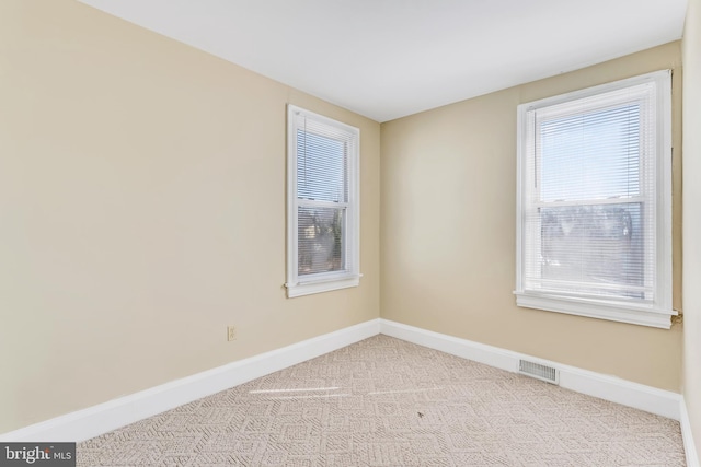 carpeted spare room featuring baseboards and visible vents