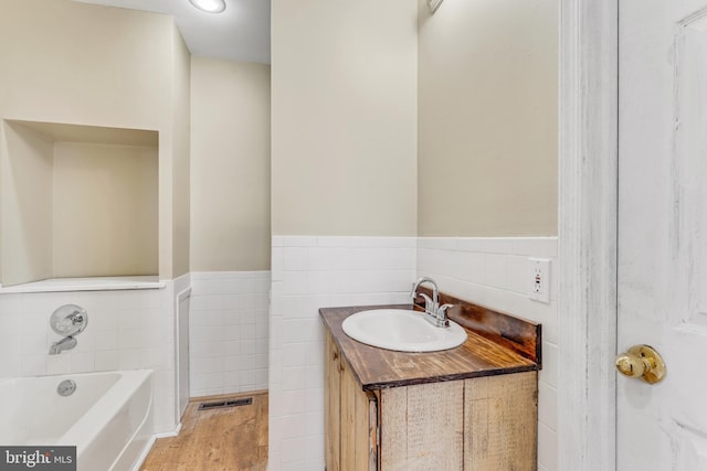 bathroom featuring visible vents, wainscoting, a bath, and tile walls