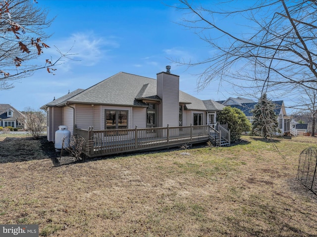 rear view of house featuring a yard, a shingled roof, a chimney, and a wooden deck