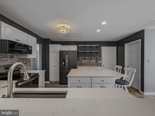 kitchen featuring stainless steel appliances, light countertops, white cabinetry, and decorative backsplash