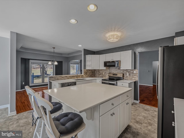 kitchen with tasteful backsplash, light countertops, appliances with stainless steel finishes, white cabinets, and a sink