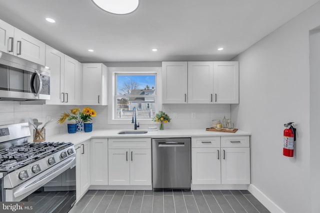 kitchen featuring appliances with stainless steel finishes, light countertops, a sink, and decorative backsplash