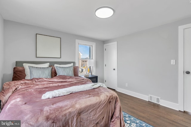 bedroom with baseboards, visible vents, and dark wood finished floors