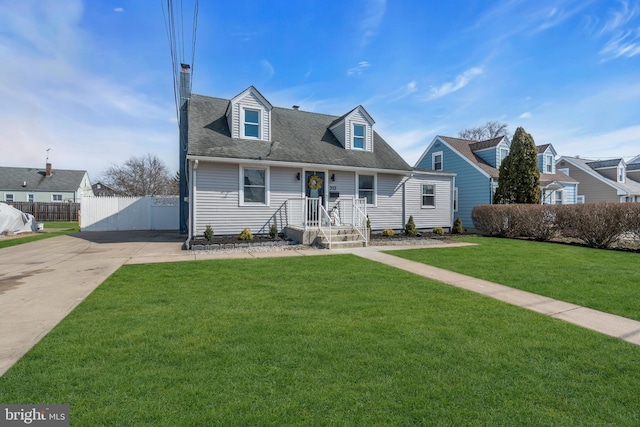 new england style home with roof with shingles, a front yard, and fence