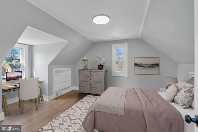 bedroom with vaulted ceiling, wood finished floors, and baseboards