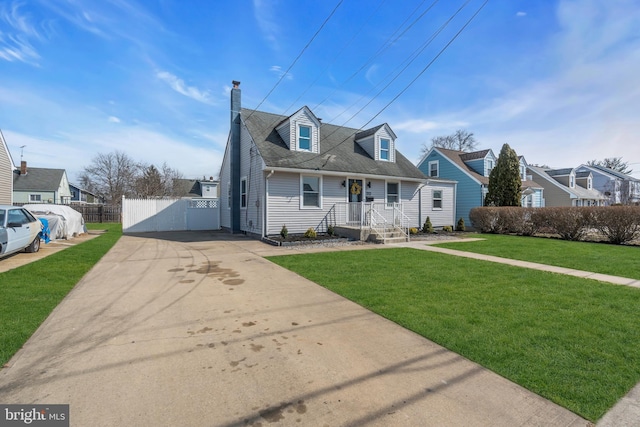 cape cod house featuring a shingled roof, concrete driveway, a chimney, fence, and a front lawn