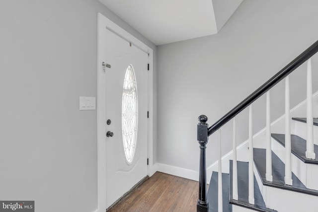 foyer entrance with plenty of natural light, stairs, baseboards, and dark wood-type flooring