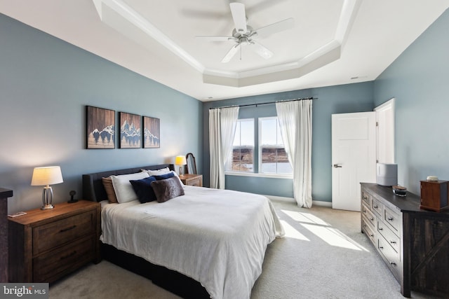 bedroom featuring crown molding, baseboards, ceiling fan, light colored carpet, and a tray ceiling