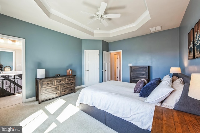 carpeted bedroom featuring a tray ceiling, baseboards, visible vents, and a ceiling fan