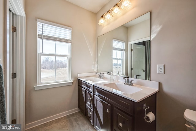 full bathroom with a sink, baseboards, double vanity, and tile patterned floors