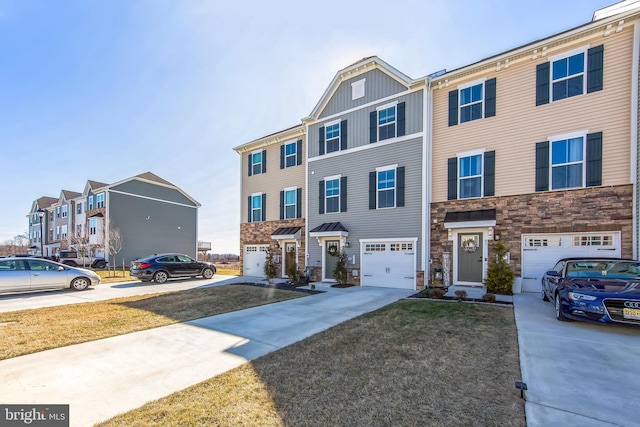 townhome / multi-family property with stone siding, a residential view, a garage, and driveway