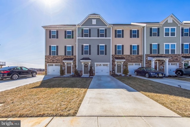 multi unit property featuring stone siding, driveway, an attached garage, and a front yard