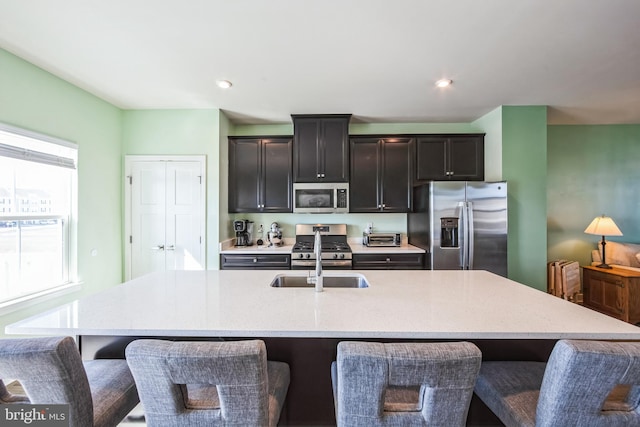 kitchen featuring a breakfast bar, an island with sink, appliances with stainless steel finishes, and a sink