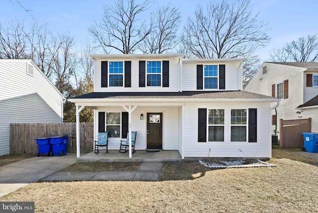 view of front of property with covered porch, fence, and a front lawn