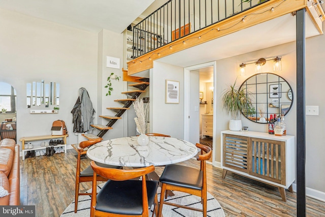 dining room with a towering ceiling, stairway, baseboards, and wood finished floors