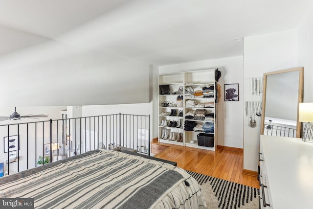 bedroom with a closet, wood-type flooring, vaulted ceiling, and baseboards