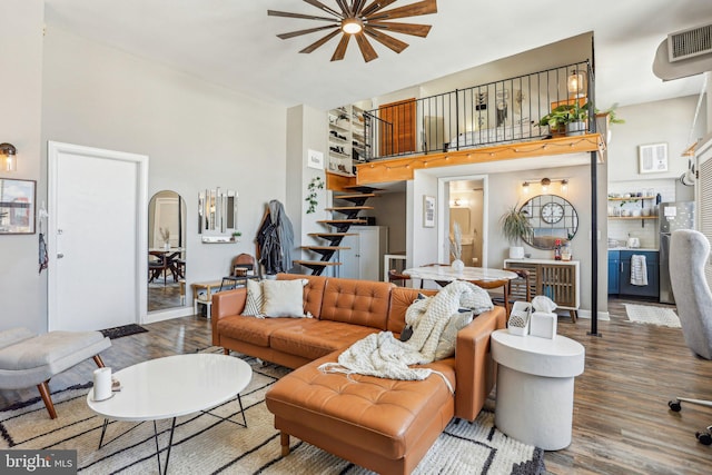 living area with visible vents, stairway, a towering ceiling, wood finished floors, and baseboards