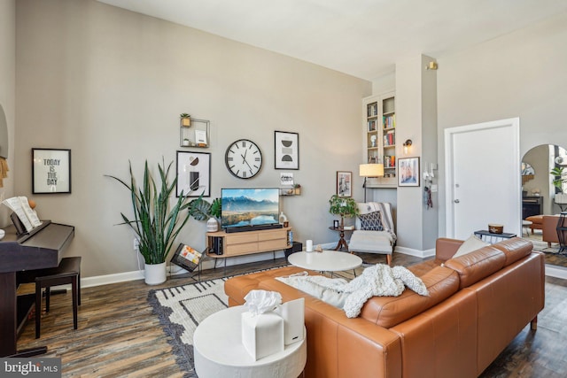 living room with baseboards, arched walkways, and wood finished floors