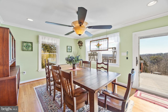 dining room featuring a healthy amount of sunlight, baseboards, light wood finished floors, and ornamental molding