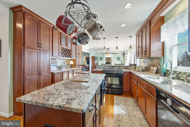 kitchen featuring black appliances, a center island, light stone countertops, and a sink