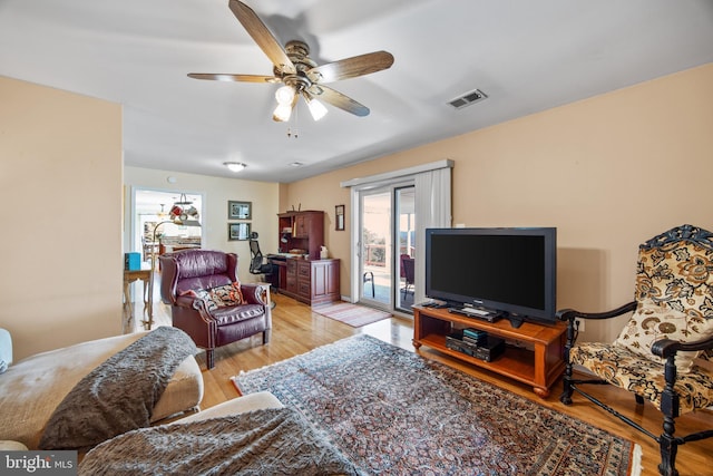 living area with a ceiling fan, visible vents, and light wood finished floors