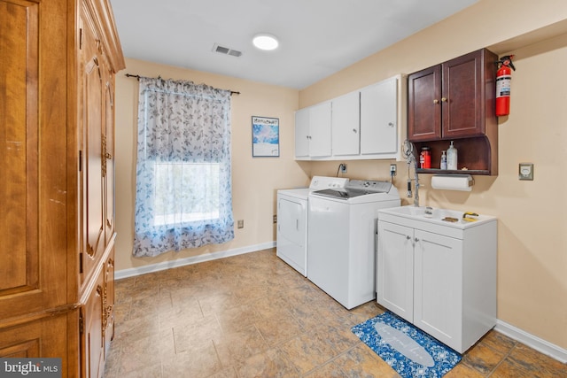 clothes washing area featuring visible vents, baseboards, cabinet space, separate washer and dryer, and stone finish floor