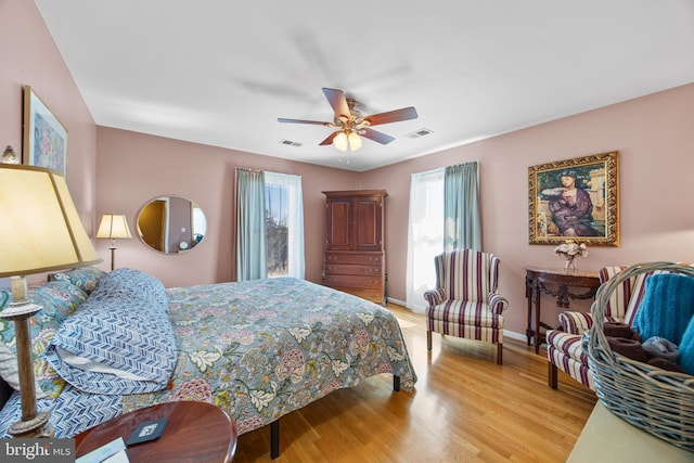 bedroom with a ceiling fan, visible vents, baseboards, and light wood finished floors