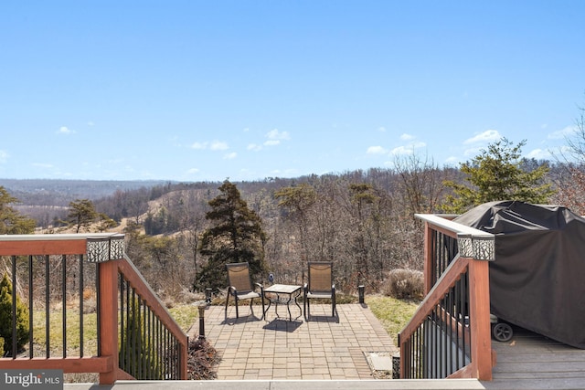 deck with a patio area, area for grilling, and a wooded view