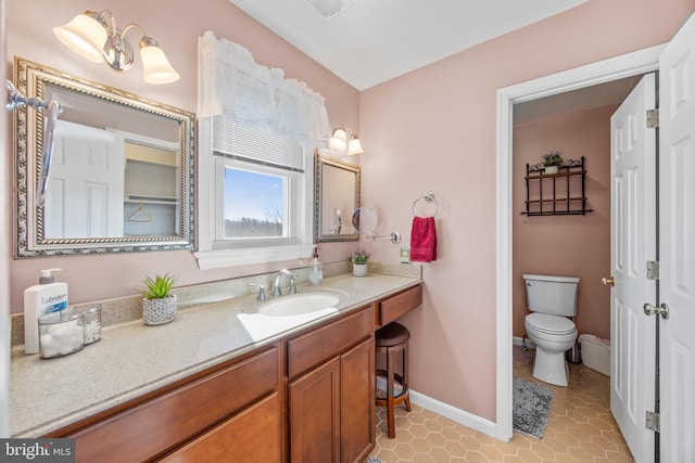 bathroom featuring visible vents, baseboards, toilet, tile patterned floors, and vanity