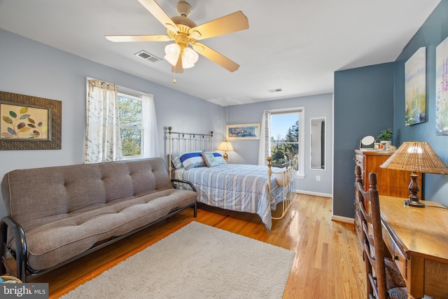 bedroom with ceiling fan, wood finished floors, visible vents, and baseboards