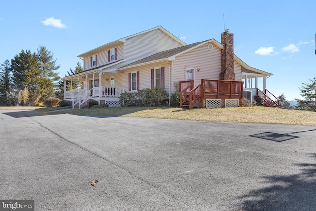 exterior space with covered porch, a lawn, and a chimney