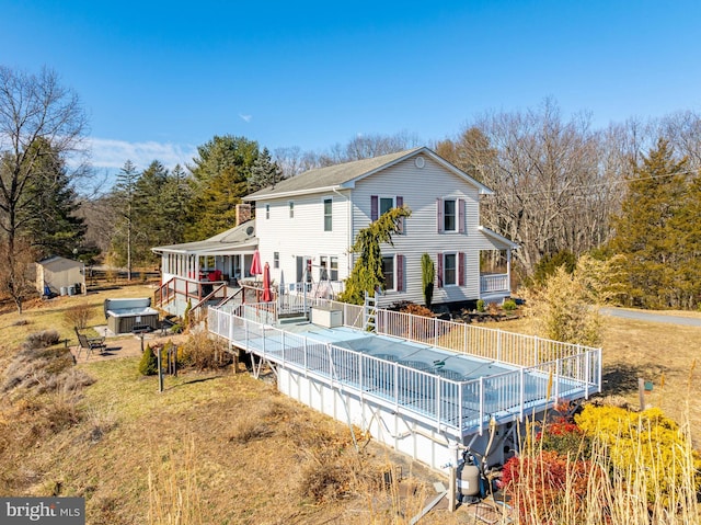 back of house with a storage unit, a wooden deck, and an outbuilding