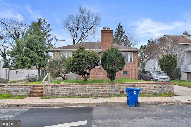 4103 Parkwood Ave, Baltimore, MD 21206 - view of front of house with brick siding, fence, a shingled roof, and a chimney