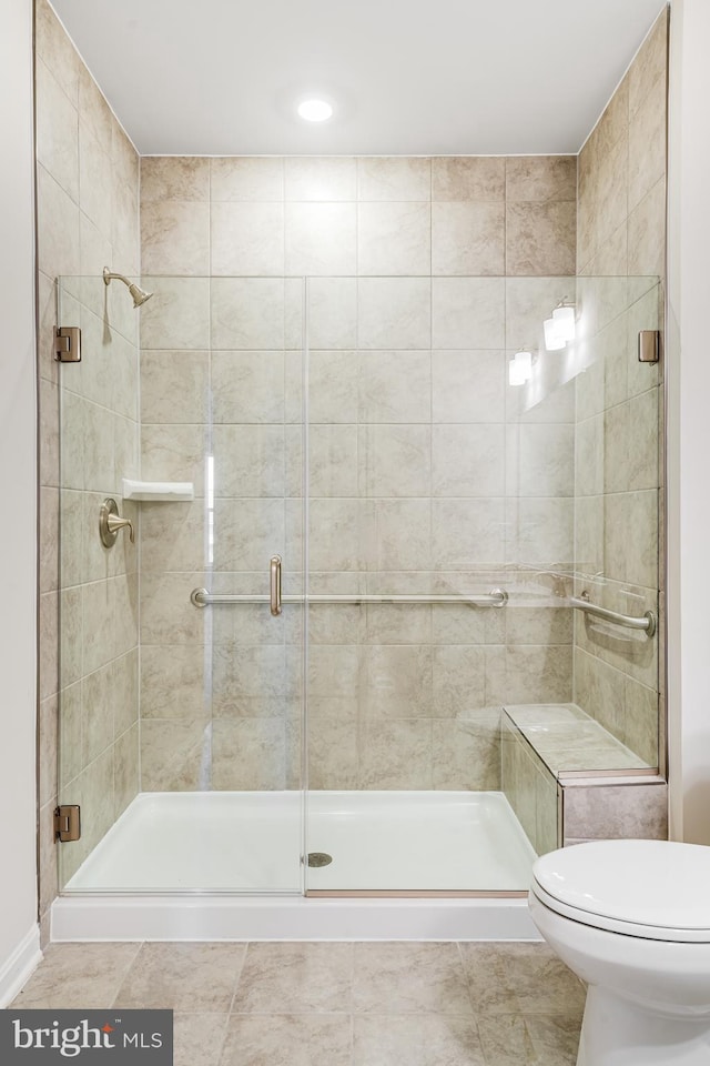 bathroom featuring a shower stall, toilet, and tile patterned floors