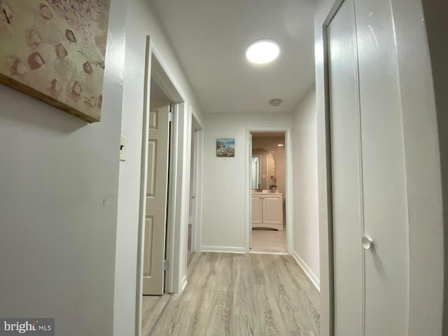 hallway featuring baseboards and light wood-style floors