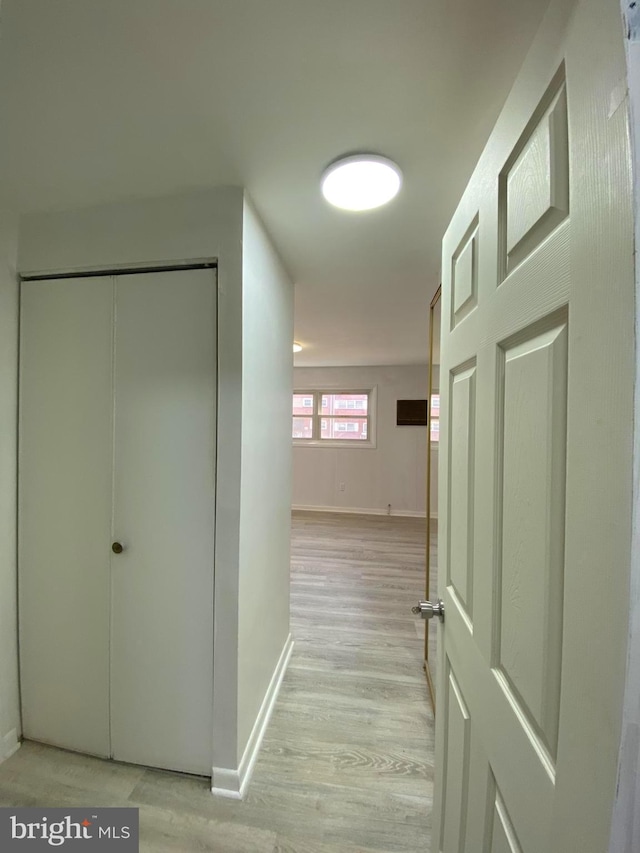 hallway featuring light wood-type flooring and baseboards