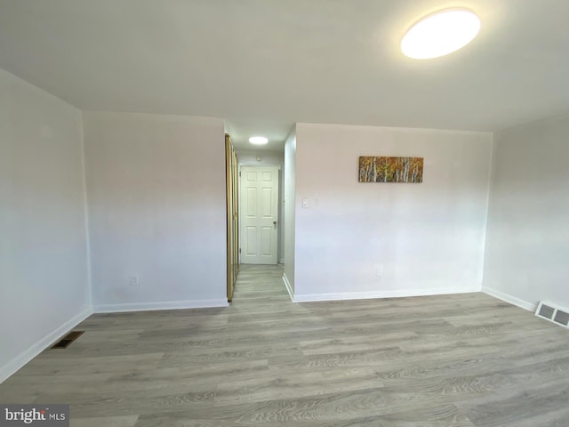 empty room featuring visible vents, baseboards, and wood finished floors