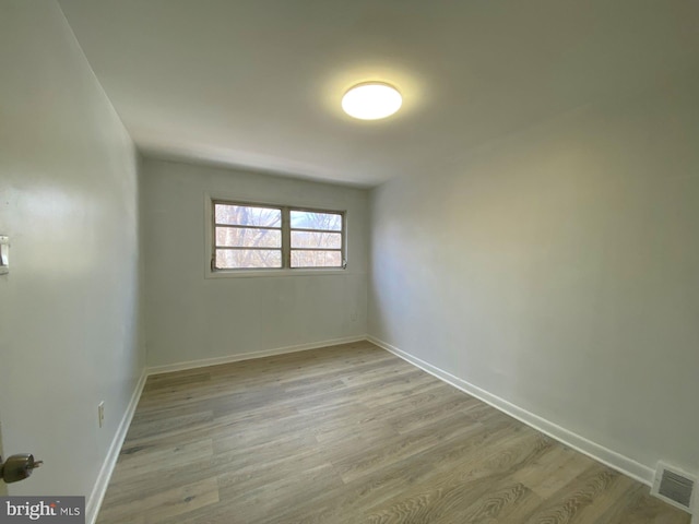 empty room featuring light wood finished floors, baseboards, and visible vents