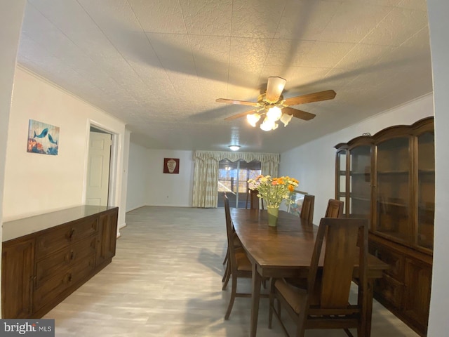 dining space with ceiling fan and light wood-style flooring