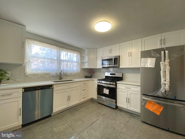 kitchen with a sink, white cabinets, light countertops, appliances with stainless steel finishes, and open shelves