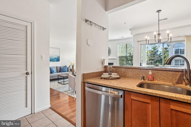 kitchen featuring light tile patterned floors, a sink, brown cabinets, light stone countertops, and dishwasher