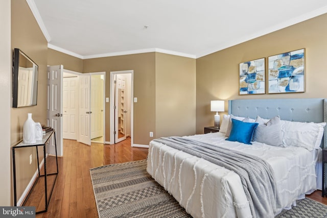 bedroom featuring baseboards, ornamental molding, and wood finished floors