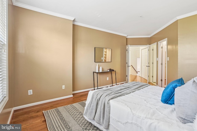 bedroom featuring baseboards, wood finished floors, and crown molding